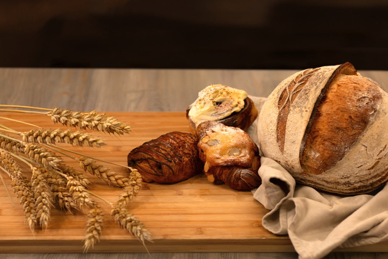 Pantry d’Or sourdough and pastries on a wooden board with wheat